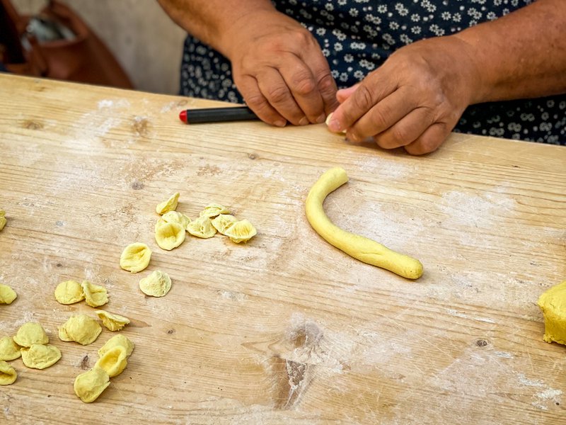 A woman's hands make pasta on a street in Bari.